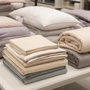 Folded sheets, pillows, and bedding sets arranged on a tidy table in store