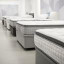 Pocket sprung and hybrid mattresses lined up in a bright showroom aisle